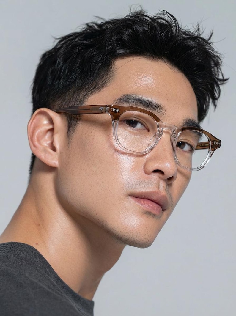 May include: Clear-framed eyeglasses with brown temples. The glasses have a square shape and are worn by a person. The image is a close-up shot, highlighting the details of the eyewear.