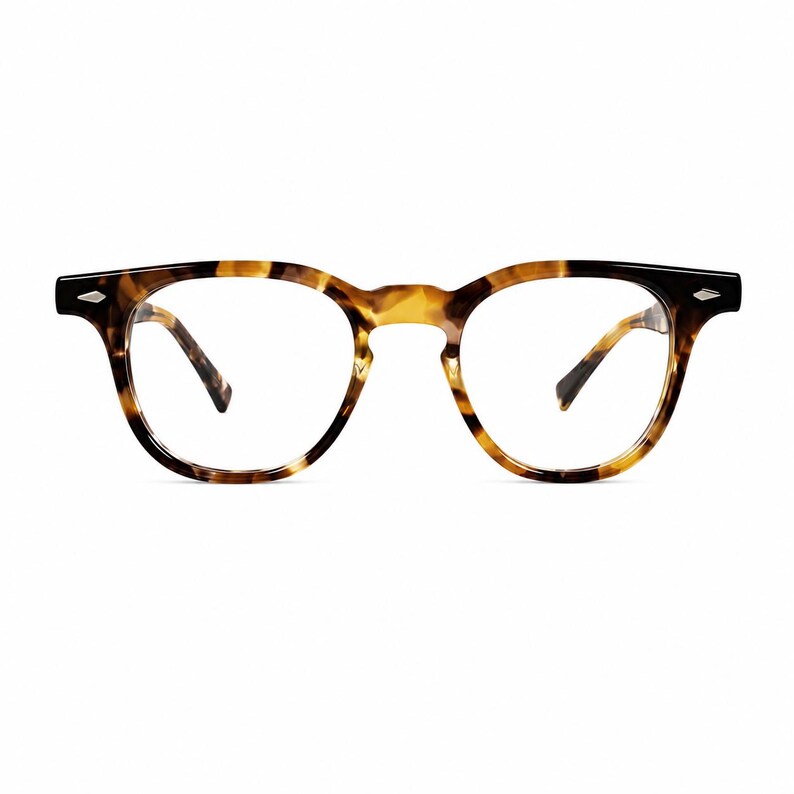 Puede incluir: Gafas de montura redonda con un patr&oacute;n de carey. Las monturas presentan una combinaci&oacute;n de tonos marrones, negros y amarillos. Las patillas son finas y oscuras, y las lentes son transparentes. Las gafas tienen una est&eacute;tica cl&aacute;sica y vintage.