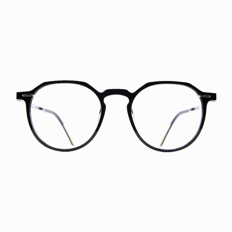 May include: Black round-frame eyeglasses with clear lenses. The glasses have a thin, minimalist design with a bridge connecting the two lenses. The temples are thin and extend to the ear. The glasses are set against a white background.