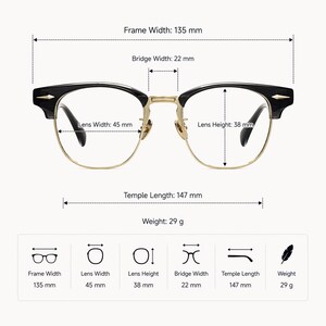 May include: Black and gold browline glasses with clear lenses. Dimensions: frame width 135 mm, bridge width 22 mm, lens width 45 mm, lens height 38 mm, temple length 147 mm, and weight 29 g. The frame features gold metal accents and black upper rims.