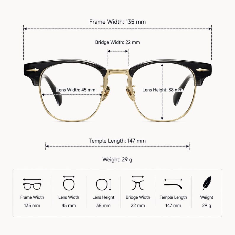 May include: Black and gold browline glasses with clear lenses. Dimensions: frame width 135 mm, bridge width 22 mm, lens width 45 mm, lens height 38 mm, temple length 147 mm, and weight 29 g. The frame features gold metal accents and black upper rims.