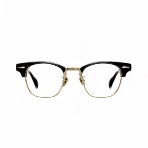 May include: Browline glasses featuring black upper frames and a gold-tone metal lower rim. The design includes gold-tone metal bridge and nose pads, with small gold-tone arrow-shaped accents on the outer corners of the black brow pieces.