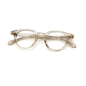 May include: A pair of clear, round-framed eyeglasses. The frames are a light, translucent brown color. The glasses have a classic, vintage design, with a keyhole bridge and subtle detailing on the temples.