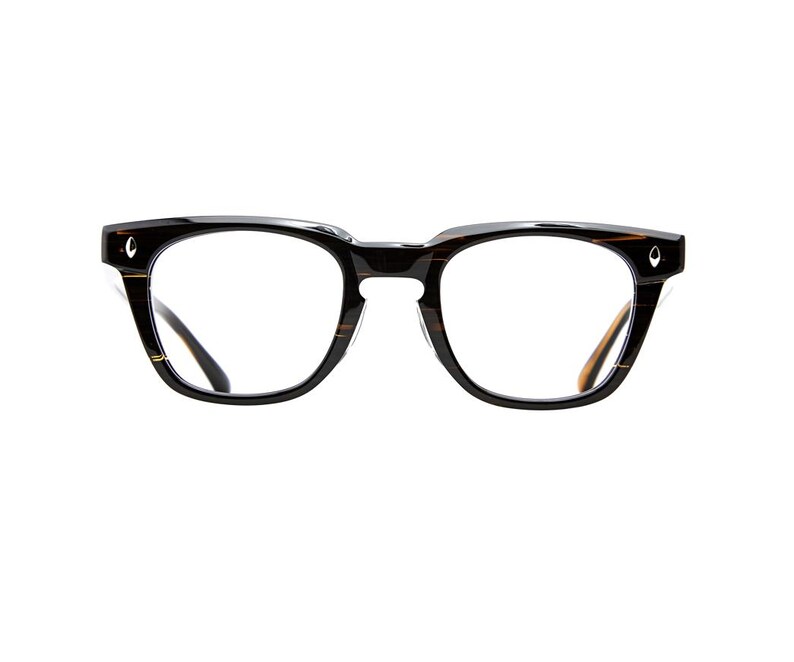 May include: Eyeglasses with a thick, dark brown and black tortoise shell patterned frame. The lenses are clear and rectangular with rounded edges. Each outer corner of the frame features a small, silver-toned, diamond-shaped metal accent.