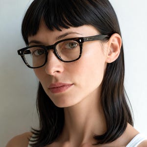 May include: Full-rim eyeglasses featuring a dark brown and black tortoiseshell pattern frame. The rectangular lenses are clear, and the frame includes small silver-toned metal rivets on the front corners and temples for a classic, structured look.