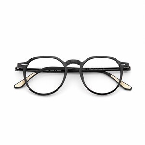 May include: Black eyeglasses with a round frame design. The glasses have a matte finish and feature a subtle gold accent on the temples. The text "MADE IN KOREA" is visible on the frame.