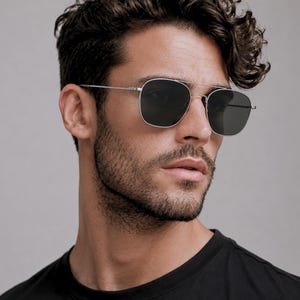 May include: Silver-toned metal sunglasses featuring a double bridge design and square-shaped dark grey lenses. The frames have thin, straight temples and adjustable nose pads, providing a clean and structured look for these classic eyewear pieces.