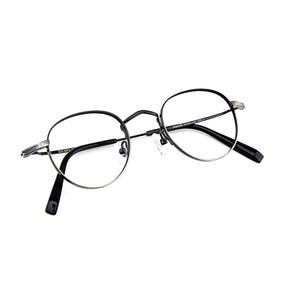 May include: Round eyeglasses featuring a thin, dark metallic frame with a silver-toned finish on the outer edges. The glasses have clear lenses, a bridge, adjustable nose pads, and black temple tips. Text is printed on the inner temple arms.