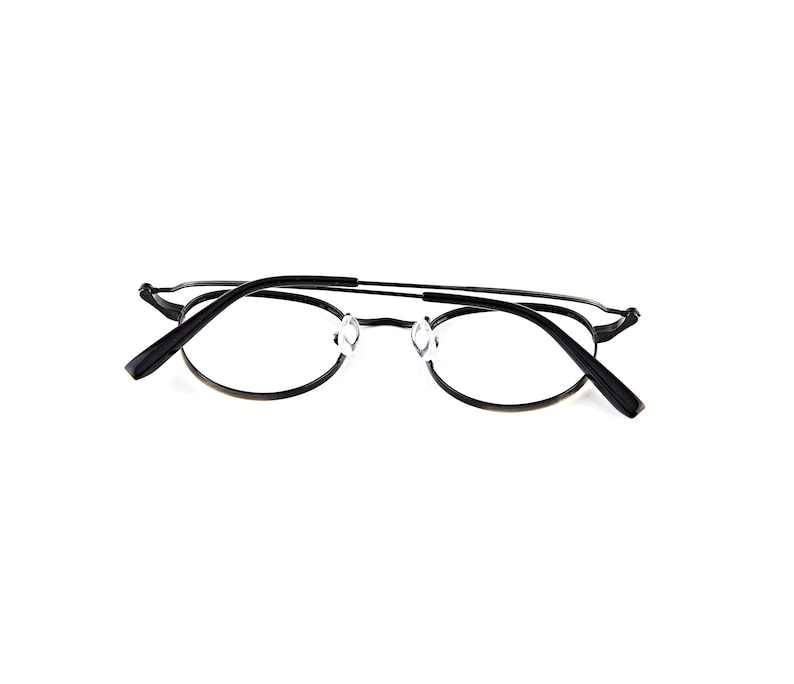 May include: A pair of black metal eyeglasses featuring thin, oval-shaped frames and a slender bridge. The glasses include clear nose pads and black temple arms with curved ends, presented from a rear-facing perspective showing the inner structure.