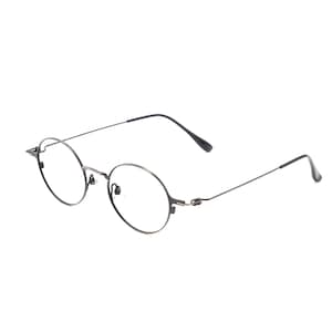 May include: Round eyeglasses featuring a thin, dark metallic frame with a bridge, adjustable nose pads, and slender temples that curve at the ends. The lenses are clear and circular, held in place by a lightweight wire structure that connects to the arms.