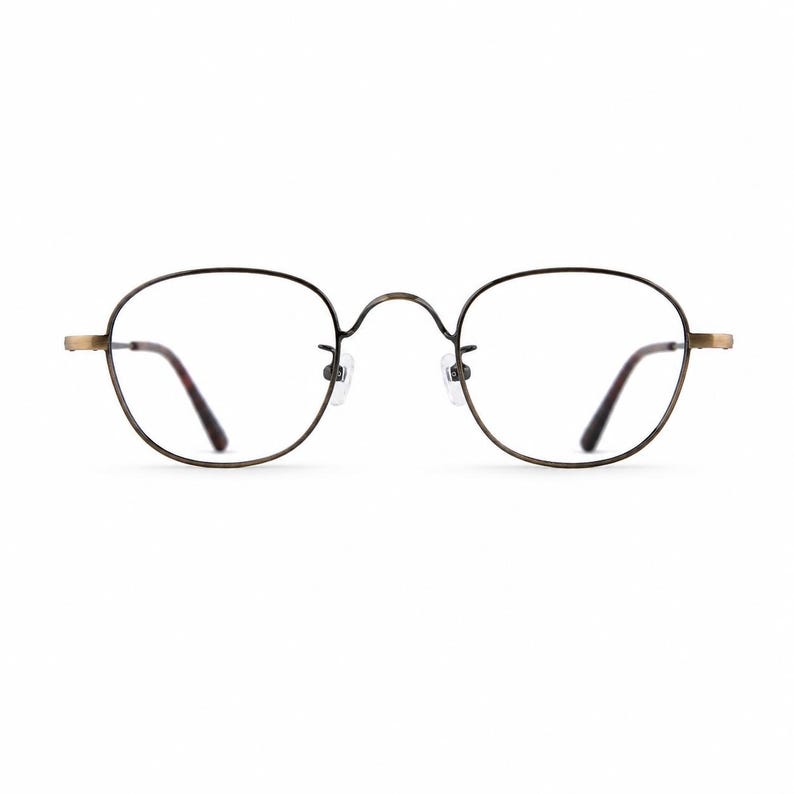 May include: Round eyeglasses with a dark brown metal frame and clear lenses. The temples and nose bridge are a lighter gold color. The lenses have a slight tint of brown. The glasses are designed for vision correction.