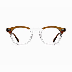 May include: Clear eyeglasses with a brown upper frame and temples. The glasses have a classic, round shape and are set against a white background. The lenses are clear, and the frame is a combination of clear and brown plastic.