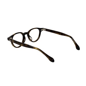 Może przedstawiać: Okulary w okrągłych oprawkach z wzorem w kolorze ż&oacute;łwia. Okulary mają ciemnobrązową i bursztynową kolorystykę, o klasycznym designie. Zauszniki są delikatnie zakrzywione, a soczewki są przezroczyste.