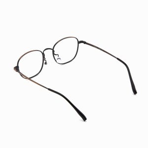 May include: Oval-framed eyeglasses in black and bronze. The lenses are clear, and the temples are bronze, fading to black at the ends. The glasses are set against a white background.