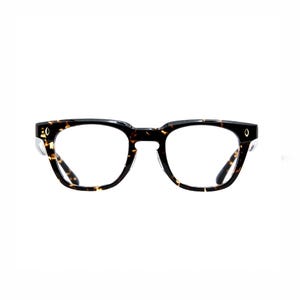Puede incluir: Gafas con un patr&oacute;n de carey cl&aacute;sico. Las monturas son una mezcla de negro y marr&oacute;n, con forma cuadrada y lentes transparentes. Peque&ntilde;os detalles plateados son visibles en las patillas.