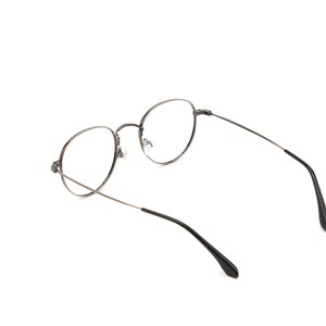 Puede incluir: Un par de gafas con monturas redondas y finas de metal color gris plomo y lentes transparentes. Las varillas son delgadas y oscuras, con puntas de pl&aacute;stico negro en los extremos. El puente es curvo, uniendo los dos aros circulares.