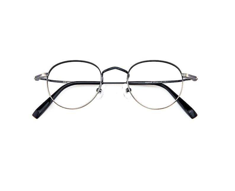 May include: Round eyeglasses featuring a thin black metal frame with silver-toned accents at the hinges and bridge. The temples are black with a glossy finish, and the clear lenses are held by a delicate wire rim. The frame includes adjustable nose pads.