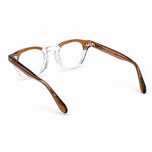 May include: Clear eyeglasses with brown temples and a round frame. The glasses have a transparent frame around the lenses and brown arms. The glasses are designed for vision correction and are suitable for everyday use.