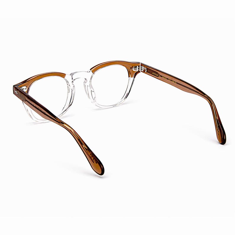 May include: Clear eyeglasses with brown temples and a round frame. The glasses have a transparent frame around the lenses and brown arms. The glasses are designed for vision correction and are suitable for everyday use.