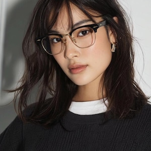 May include: Browline glasses featuring a thick black upper frame and a thin gold-tone metal lower rim. The design includes clear lenses, gold-tone nose pads, and small silver-tone metal accents on the outer corners of the black brow pieces.