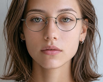 May include: Round eyeglasses with a thin, dark metallic frame and clear lenses. The glasses feature a simple bridge design and slender temples that extend to the sides, providing a clean and functional look for everyday vision correction needs.