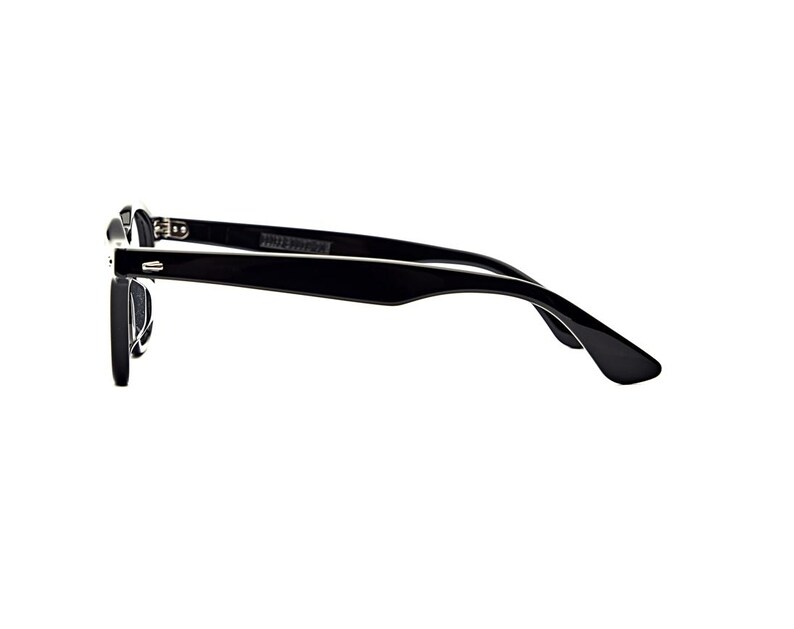 May include: A pair of black-framed eyeglasses shown from a side profile view. The frames feature a glossy black finish with a classic rectangular shape, curved temple arms, and visible silver-toned metal hinges connecting the front to the arms.