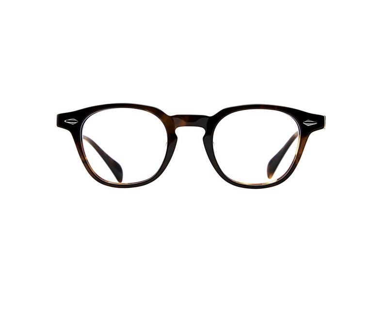 May include: Tortoiseshell-patterned eyeglasses with a rounded frame shape. The frames feature a dark brown and amber mottled finish with clear lenses. Small silver-toned diamond-shaped accents are visible on the outer corners of the frame front.