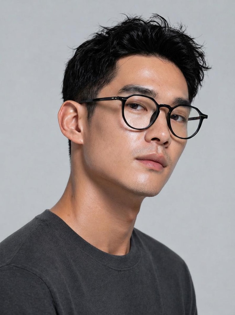 May include: Black round-frame eyeglasses. The glasses have a classic design with a thin frame and are worn by a person. The background is a solid light gray.