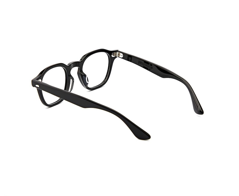 May include: Black eyeglasses with a glossy finish, featuring a rounded frame shape and thin temples. The glasses are shown from a rear-facing angle, highlighting the hinges and the smooth, curved design of the frame and arms against a white background.
