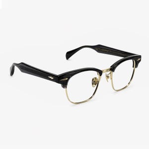 May include: Black and gold browline glasses featuring a semi-rimless design with a thin gold metal bridge and lower rims. The thick black acetate upper brow bars and temples are accented with small, pointed gold-tone metal studs at the hinges.