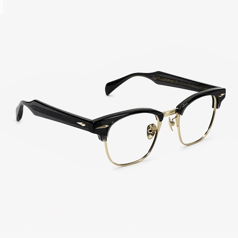 May include: Black and gold browline glasses featuring a semi-rimless design with a thin gold metal bridge and lower rims. The thick black acetate upper brow bars and temples are accented with small, pointed gold-tone metal studs at the hinges.