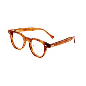 Puede incluir: Gafas con estampado de carey. Las monturas son de color marr&oacute;n c&aacute;lido con una forma cl&aacute;sica y redondeada. Las patillas son rectas y presentan un dise&ntilde;o sutil. Las gafas est&aacute;n sobre un fondo blanco.