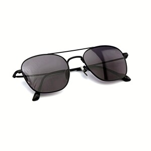 May include: Black metal frame sunglasses featuring a double bridge design and dark tinted lenses. The eyewear has a thin, lightweight construction with adjustable nose pads and curved temple tips, providing a classic look with a modern aesthetic.