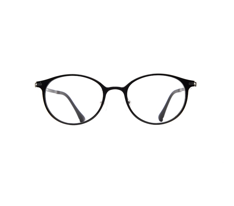 Pode incluir: Um par de &oacute;culos com arma&ccedil;&otilde;es finas, pretas e arredondadas com lentes transparentes. Os &oacute;culos t&ecirc;m uma ponte estreita que liga os dois aros circulares, com hastes pretas finas que se estendem para fora em cada lado da arma&ccedil;&atilde;o.