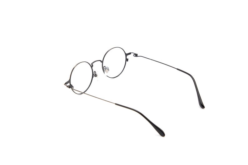 May include: A pair of eyeglasses featuring thin, dark metal frames with circular lenses. The glasses have slender temples and adjustable nose pads, showcasing a simple, lightweight construction with a matte finish on the frame structure.