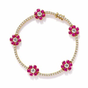 May include: A gold bracelet featuring a series of five flower-shaped designs. Each flower has a central, round, clear stone surrounded by pink stones. The bracelet's band is adorned with small, clear stones.