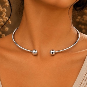 Collana girocollo minimalista in argento sterling con apertura a sfera e design a torsione.