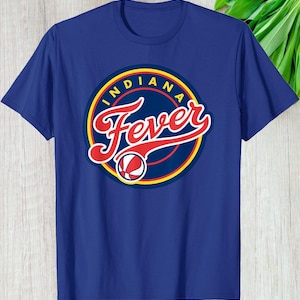 May include: Blue t-shirt featuring a circular logo with the text "INDIANA Fever" in red script and a basketball graphic. The logo is outlined in yellow and white, set against a navy blue background.