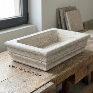 May include: A rectangular, light-coloured stone planter with a textured surface. The planter is 50cm long, 30cm wide, and 13cm high. It sits on a wooden surface. The text on the image reads: L: 50cm | P: 30cm | H: 13cm.