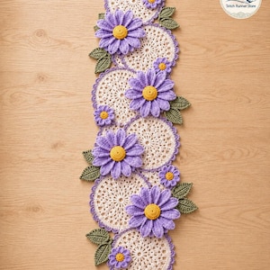 May include: A long, vertical crochet table runner featuring a series of circular, cream-colored doilies with purple scalloped edges. The runner is decorated with large, textured purple flowers with yellow centers and small green crocheted leaves.