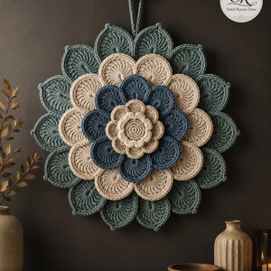May include: A circular crochet wall hanging featuring a layered floral design with concentric rings of petals in shades of teal, cream, and dark blue. The piece includes a small hanging loop at the top and displays the text SR Stitch Runner Store.