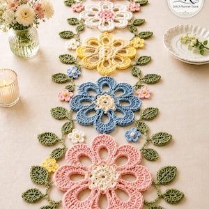 Può includere: Runner da tavolo floreale all'uncinetto. Il runner presenta grandi fiori traforati nei toni del rosa, bianco, giallo e blu, collegati da viti verdi con foglie e piccoli fiori. Una candela e un vaso di fiori sono sullo sfondo.