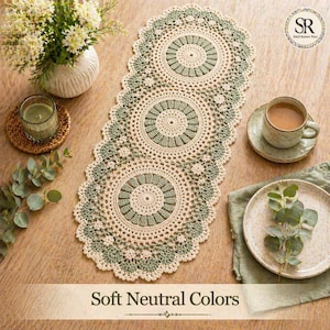 Puede incluir: Un camino de mesa de ganchillo color crema con tres diseños circulares grandes y un borde festoneado. Los diseños circulares tienen un centro verde salvia. El texto "Soft Neutral Colors" está en la parte inferior de la imagen.