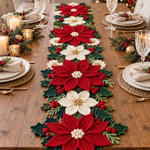 May include: A long, rectangular crochet table runner featuring alternating large red and white poinsettia flowers, dark green holly leaves, and small red berry clusters arranged in a repeating pattern along the center of a wooden dining table.