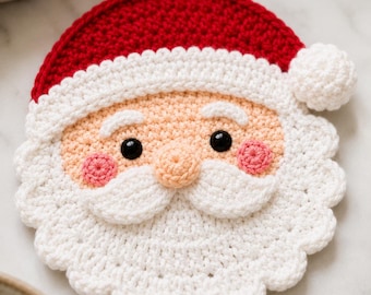 Könnte beinhalten: Ein runder, gehäkelter Untersetzer in Form eines Weihnachtsmann-Gesichts mit roter Mütze und weißem Bommel, pfirsichfarbenem Gesicht, schwarzen Kunststoffaugen, rosa Wangen sowie einem weißen Bart und Schnurrbart mit gewelltem Rand.