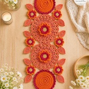 Pode incluir: Um caminho de mesa retangular em crochê com um padrão repetitivo de grandes napperons circulares laranja, motivos florais menores em tons de laranja, rosa e amarelo, e detalhes em forma de folha laranja, dispostos verticalmente.