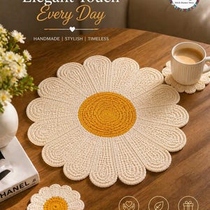 May include: A cream-coloured, daisy-shaped crochet placemat with a yellow centre, with a matching coaster and a cup of coffee. The text "Elegant Touch Every Day" is visible. The placemat is handmade and stylish.