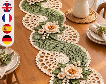 May include: A long, serpentine crochet table runner featuring a cream-colored lace pattern with a wavy, solid green center. The runner is decorated with three clusters of three-dimensional cream flowers, dark green leaves, and small white berries.