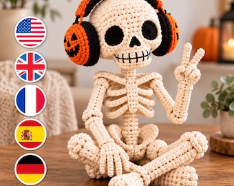May include: A crocheted skeleton figurine in an off-white yarn, sitting cross-legged and making a peace sign with one hand. The skeleton wears black and orange headphones with a jack-o'-lantern face design on the ear cups and black eye sockets.