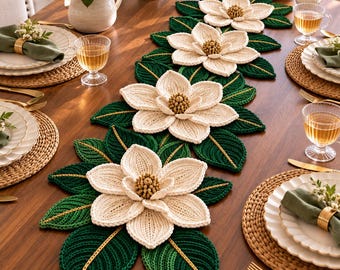 May include: A long, decorative table runner featuring four large, three-dimensional crocheted magnolia flowers with cream-colored petals and textured centers, surrounded by dark green crocheted leaves with gold-colored thread accents.